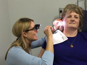 Nurse performing ear wax removal on a patient