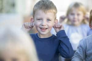 Smiling boy playing with his ears