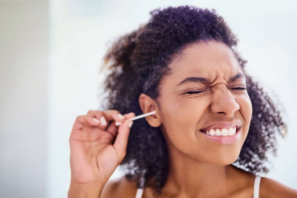 female cleaning ear with cotton bud