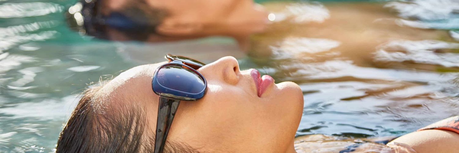 Couple swimming in pool of spa resort together